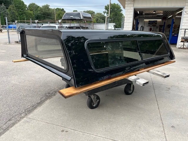 Black Chevy HD 98" truck cap with tinted windows and wooden side rail.