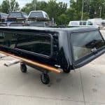 Black Chevy HD 98" truck bed cap with tinted windows and wooden side rails.
