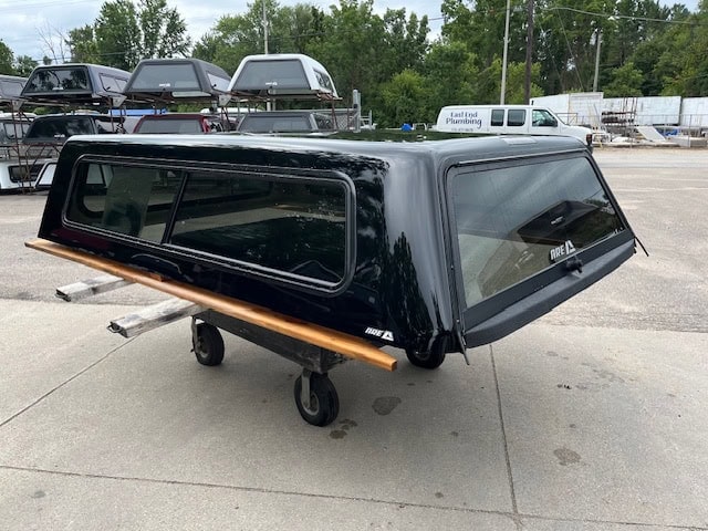 Black Chevy HD 98" truck bed cap with tinted windows and wooden side rails.