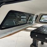 Black truck bed cover installed in a Chevy HD 98" vehicle with side windows.
