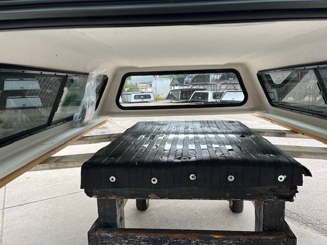 Black truck bed cover for Chevy HD 98" with wooden support structure.