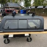 Matte black truck cap for Toyota Tacoma with window and roof rack.