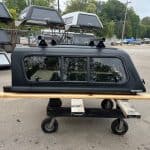 Matte black truck cap for Toyota Tacoma with window and roof rails.