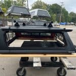 Matte black truck cap for Toyota Tacoma with tinted window and roof rack.