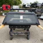 Matte black truck cap for Toyota Tacoma with side windows and rear window.