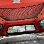 Interior view of a truck cap with storage net and windows.