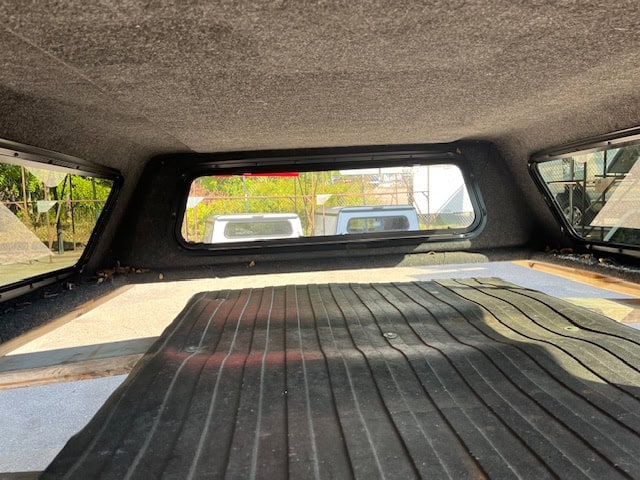 Interior view of a truck cap with a rear window and cargo area.