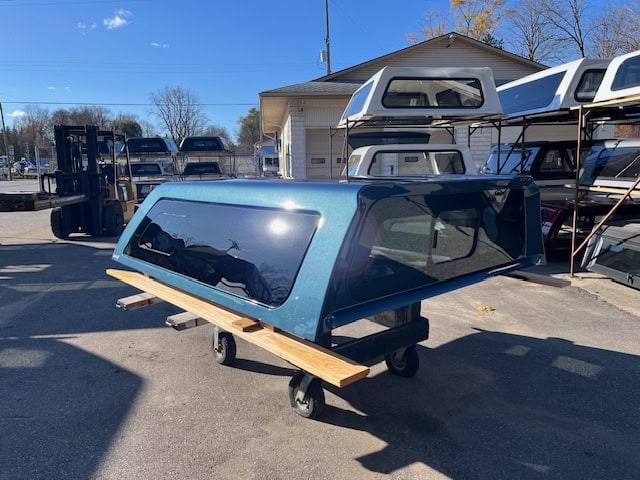 Blue truck cap with tinted windows on a cart at Camp and Cruise.