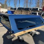 GMC HD 82.2" PNT blue truck cap with tinted windows and wooden base.