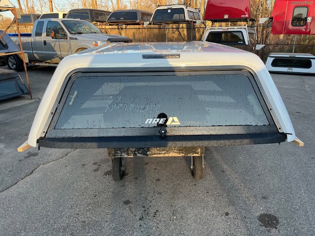 Chevy truck bed cap in Summit White with rear window and rain droplets.