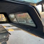 Chevy truck camper shell with black interior and side window.