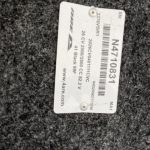 Close-up of truck part label on black textured surface.