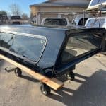 Black Chevy HD truck camper shell with tinted windows and aerodynamic design.