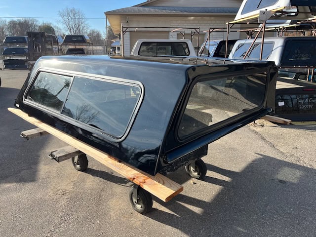 Black Chevy HD truck camper shell with tinted windows and aerodynamic design.