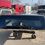 Black truck cap for Chevy HD 82.2" in a storage lot with trailers and trucks.