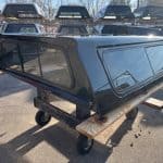 Black truck cap for GMC 1500 with tinted windows and aerodynamic design.