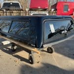 Black truck cap for GMC 1500 with tinted windows and aerodynamic design.