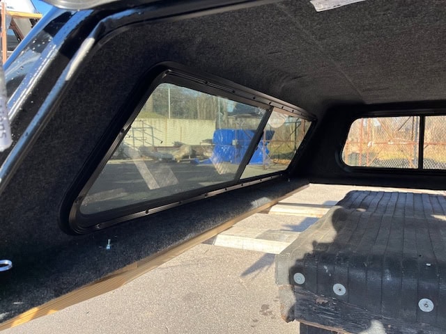 Interior view of GMC 1500 truck with bed cover and window.
