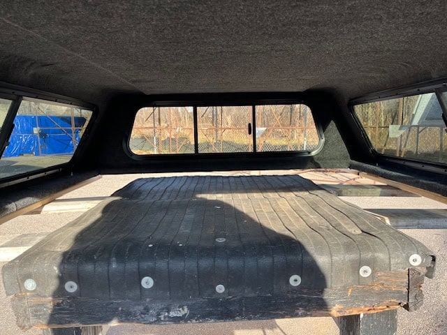 GMC 1500 truck bed with black PNT code 8555 in a truck camper shell.