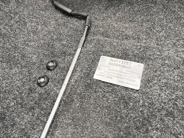 Vehicle part with label N4713757 on dark textured surface.