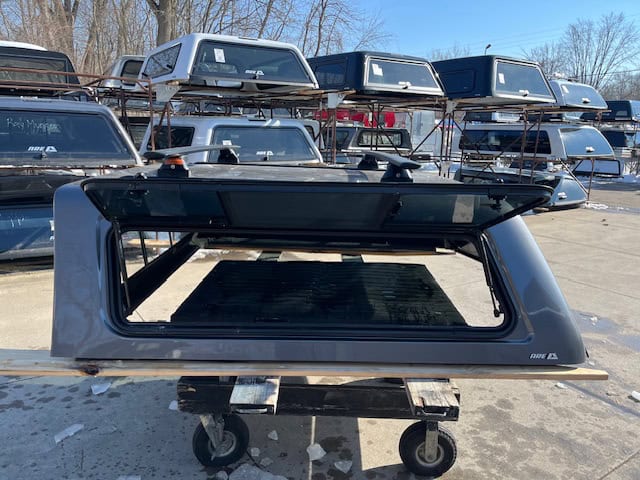 Gray truck cap for F150 with tinted window and aerodynamic design.
