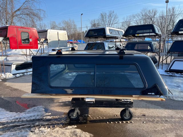 Black truck cap with side window for Ford SD 81.9" in outdoor lot.