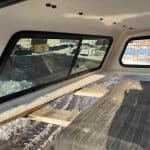 Truck bed interior with wooden platform and side windows for cargo transport.