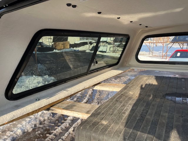 Truck bed interior with wooden platform and side windows for cargo transport.