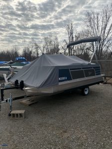 Pontoon boat covered with a protective tarp at Camp & Cruise.