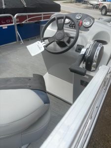 Pontoon boat steering wheel and control panel for marine navigation.