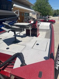 Red fishing boat with steering console and seating at Camp & Cruise.