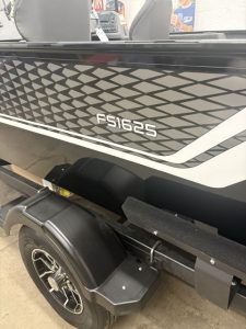 Boat with geometric patterned hull and registration FS1625 on trailer.