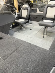 Interior view of a fishing boat with seating, storage, and fishing gear.