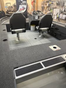 Fishing boat cockpit with two captain chairs and navigation equipment.