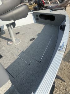 Boat interior with gray carpet, storage, and seat for fishing or leisure.