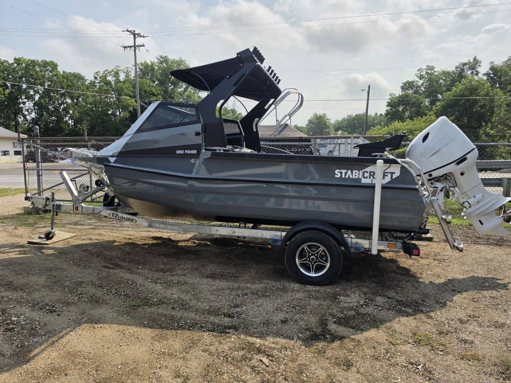Stabicraft boat with outboard motor on trailer at dealership.