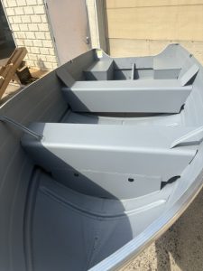 Gray fishing boat with interior seats and storage compartments.