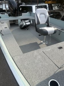 Fishing boat interior with captain's chair and controls.