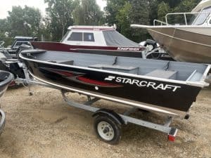 Starcraft 16 Seafarer DLX boat on trailer at boat dealership lot.