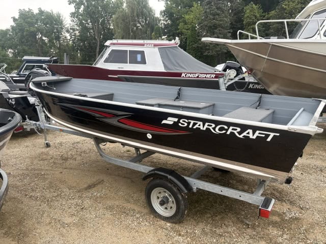 Starcraft 16 Seafarer DLX boat on trailer at boat dealership lot.