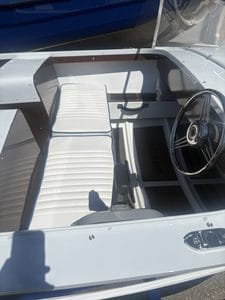 Close-up of ski boat interior with white seating and steering wheel at Camp & Cruise.