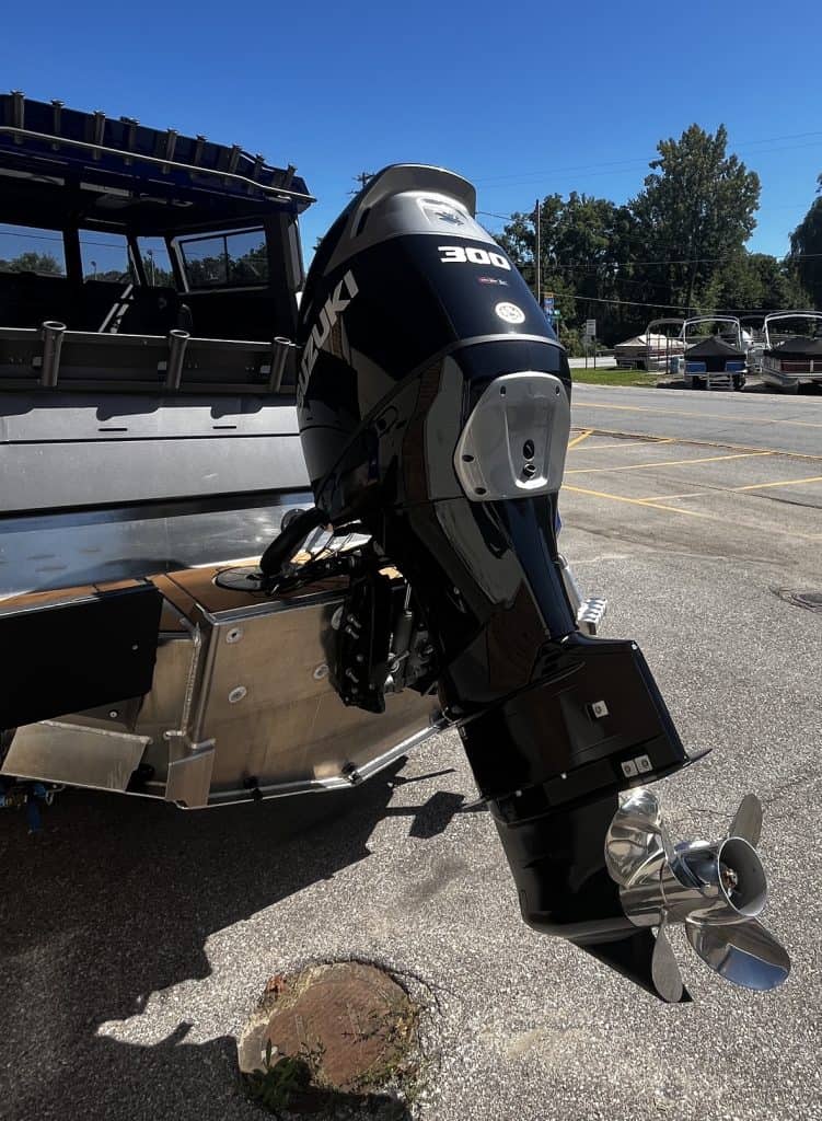 Pontoon boat with Mercury 300 outboard motor in parking lot.
