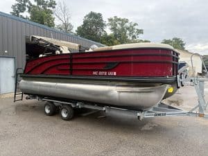 Red and black Lowe SS190 pontoon boat on trailer at marina.