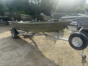 Aluminum boat on trailer at boat dealership with other boats in background.