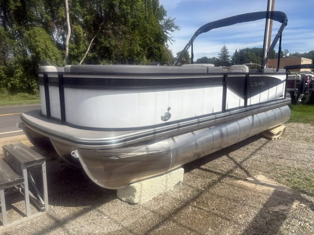 Lowe LS210 pontoon boat on land with trees in background.