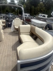 Pontoon boat seating area with beige cushions and marina background.
