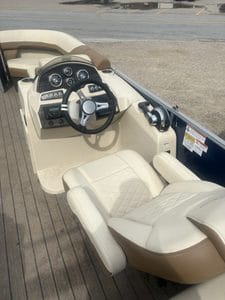 Boat helm with steering wheel and dashboard controls in a Lowe SS210.
