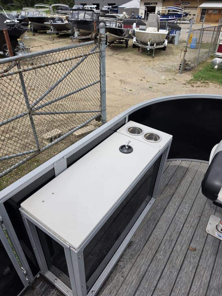 Pontoon boat with built-in cup holders and storage, docked at a marina.