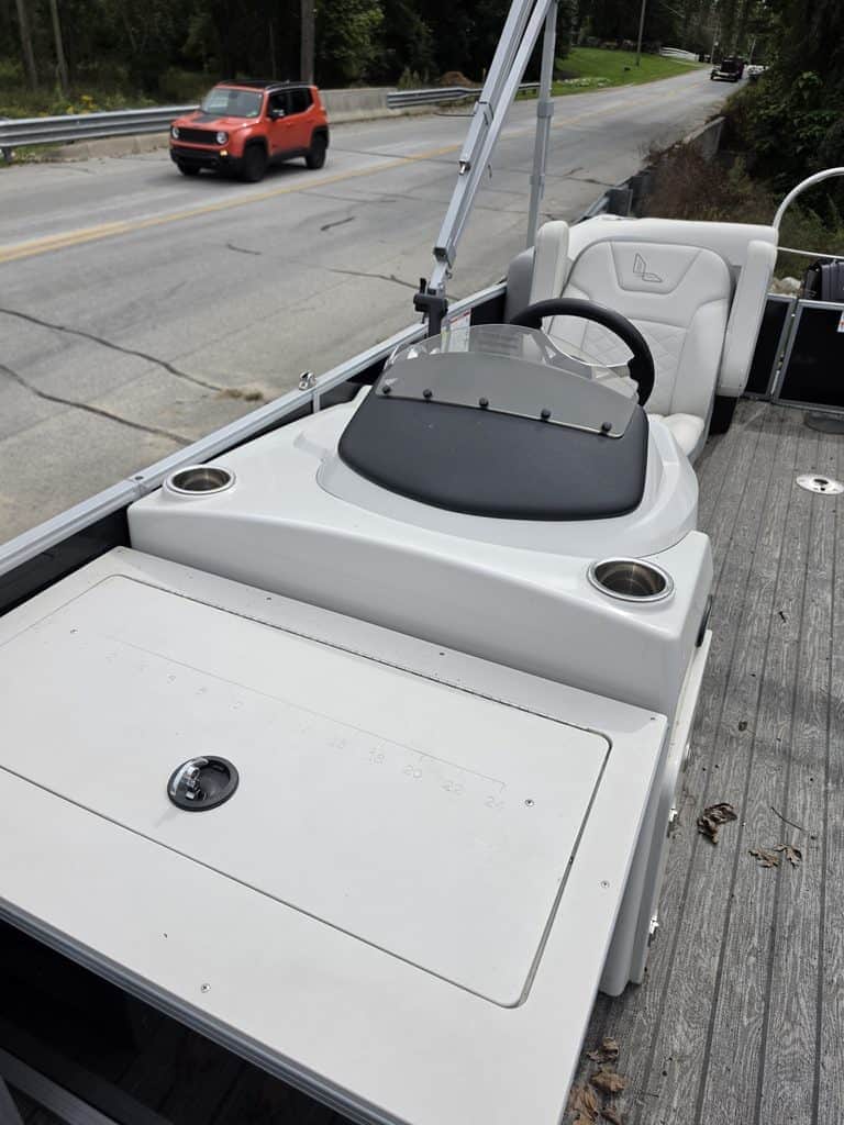Pontoon boat dashboard with steering wheel and controls on a road.