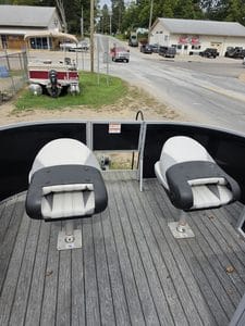View of pontoon boat seats with a street and shops in the background.